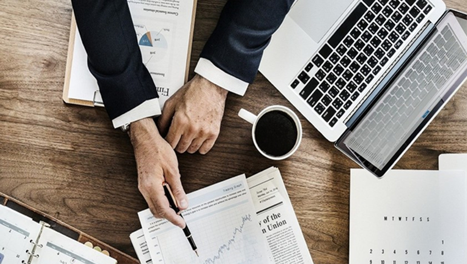 Mão de um executivo apontando para um gráfico em uma folha